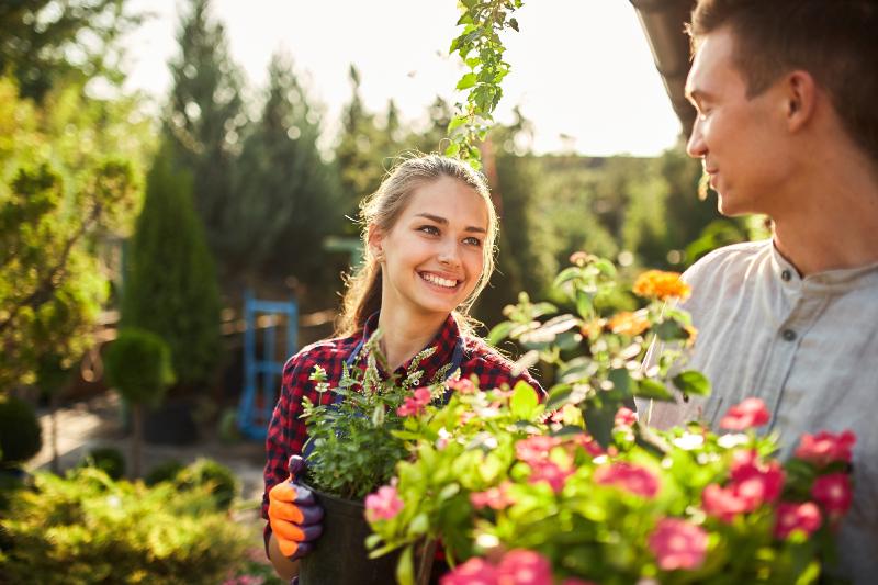 Ein junges Paar ist damit beschäftigt, Blumen und Pflanzen im Garten im heimischen Garten einzupflanzen