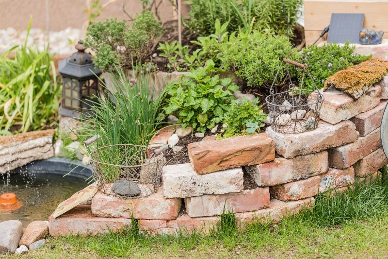 Die Pumpenanlage eines Springbrunnens im Garten ist hinter einer Mauer versteckt