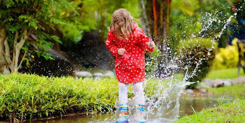 Kind-hüpft-in-einer-Pfütze-im-Garten